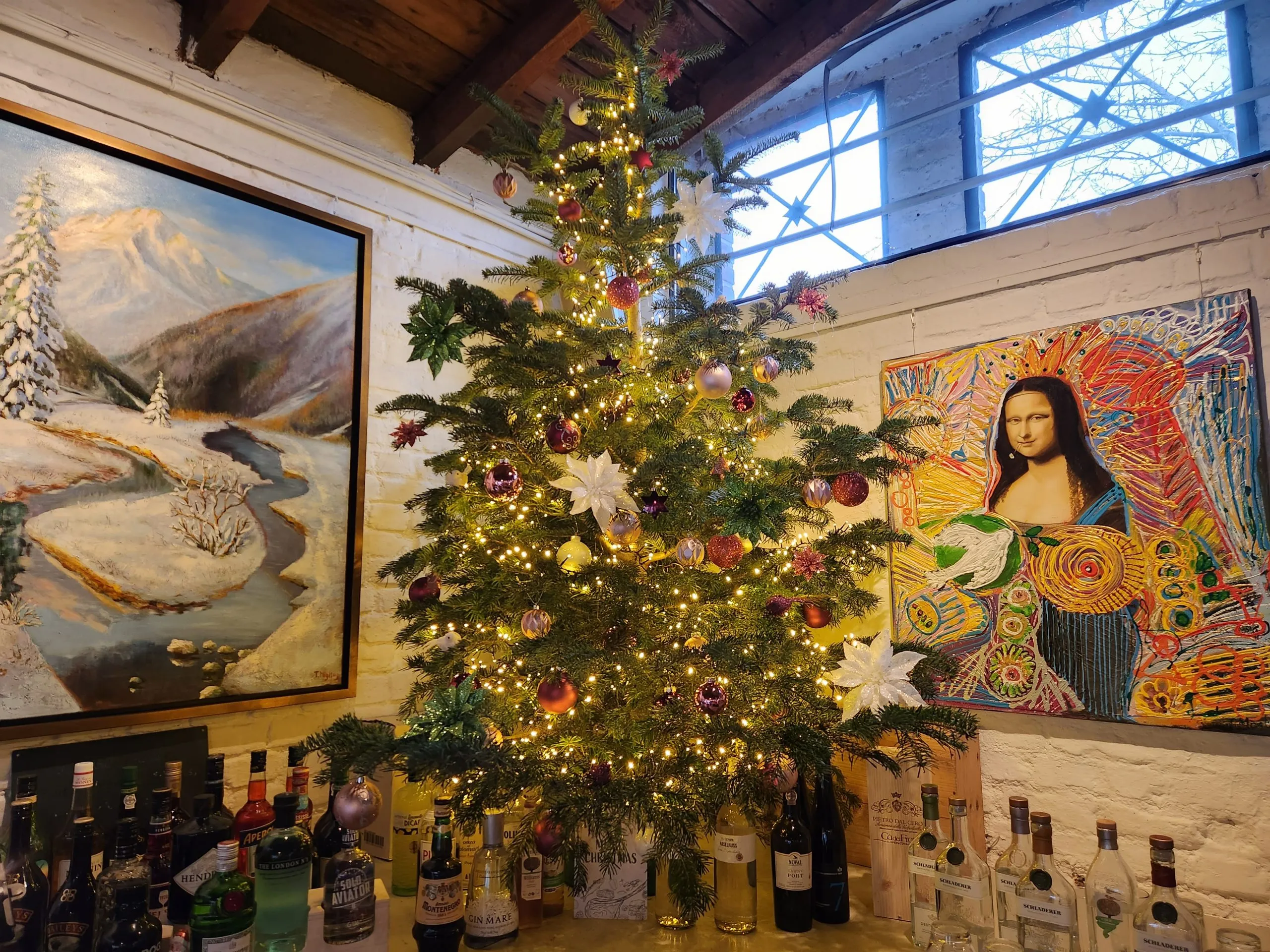 Geschmückter Weihnachtsbaum im Gastraum vor Gemälden